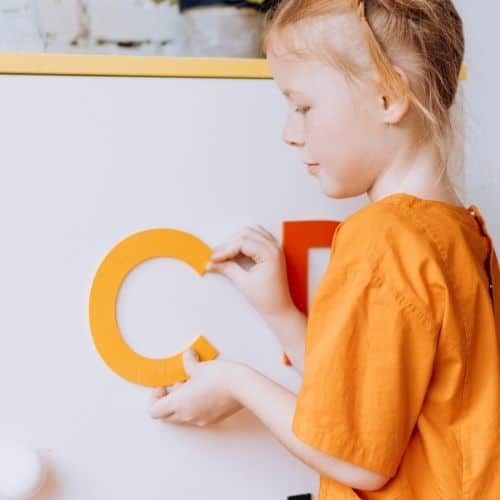 Girl using alphabet letters to spell pre primer sight words in preschool