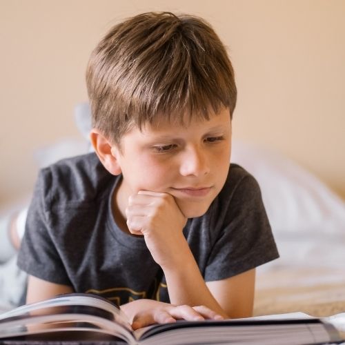 Third grade boy reading a book with sight words