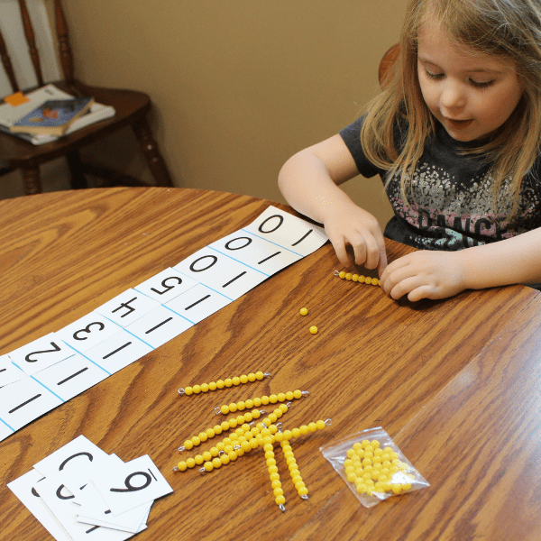 child practicing Montessori math with teens board and golden beads