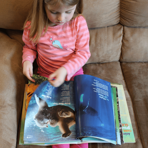 girl reading about animals with her Elementary Homeschool History Curriculum