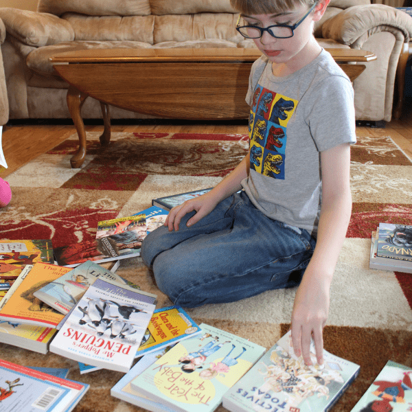 elementary aged child choosing books to read for his homeschool history curriculum